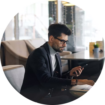 A professional man in a suit researching small business funding options on his phone in a modern café.